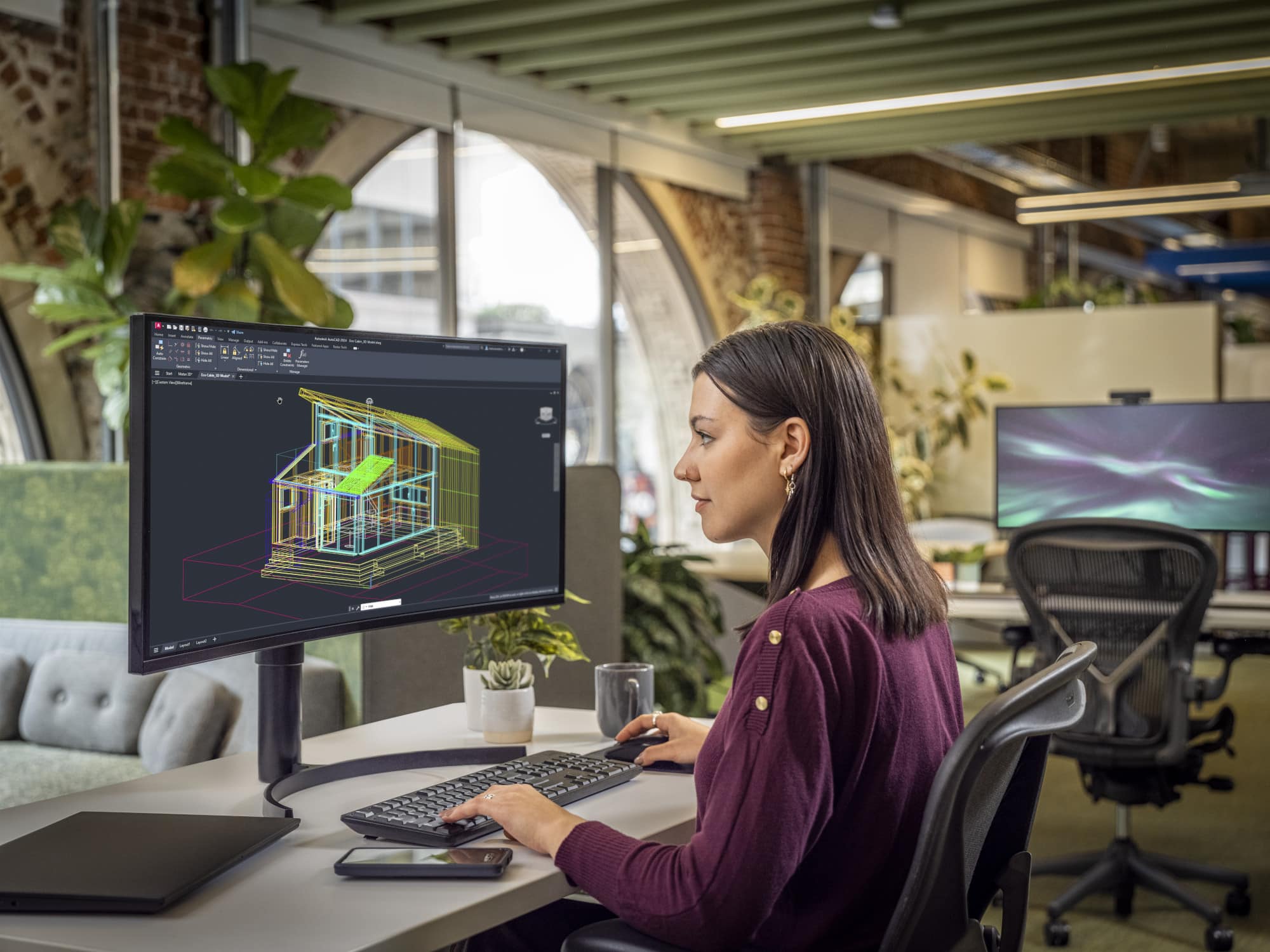 Woman using Autodesk AutoCAD LT in an office environment. Looking at a building blueprints on a screen.
