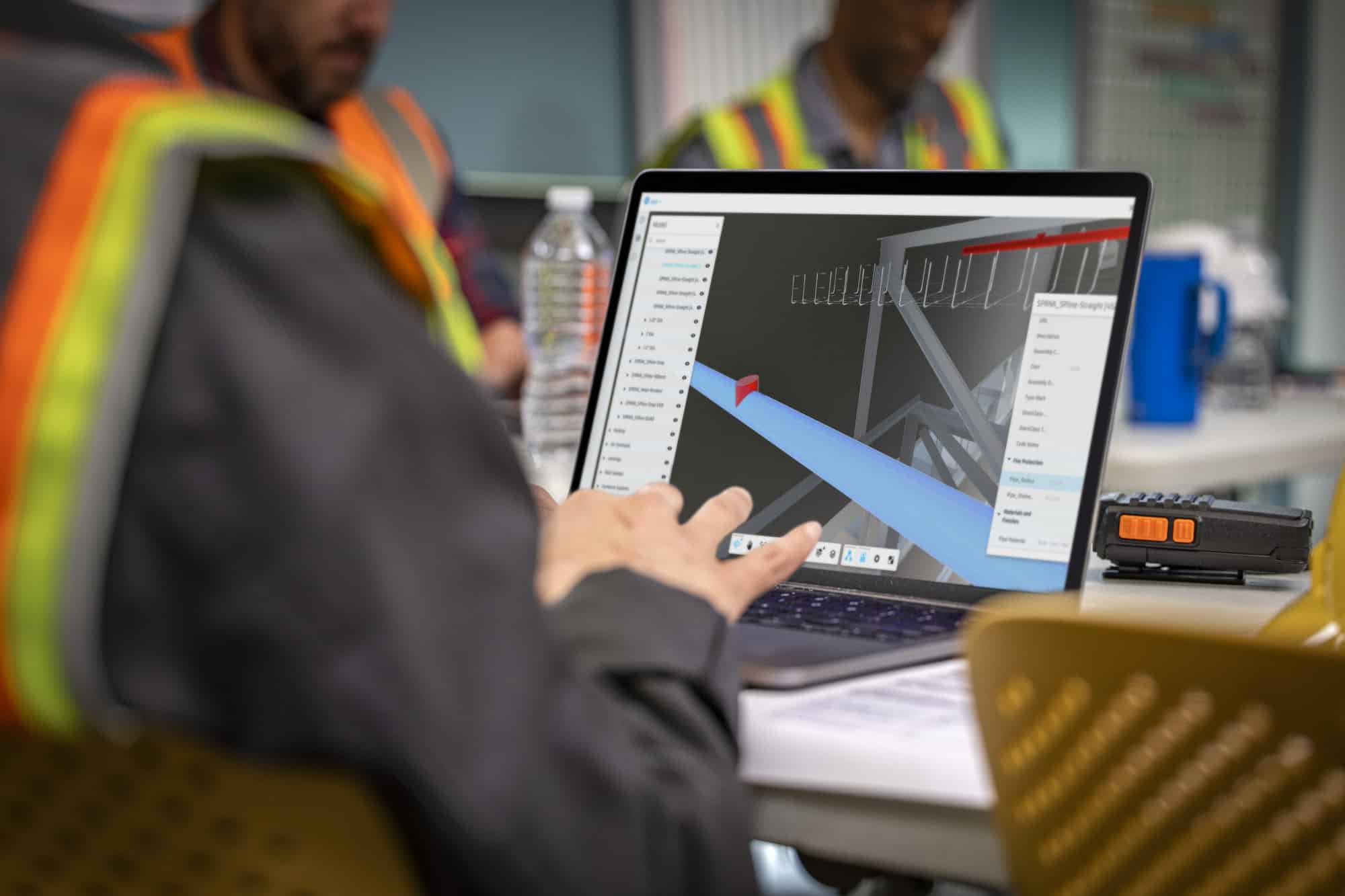 A man in a high vis jacket looking at a monitor with Navisworks on screen. 